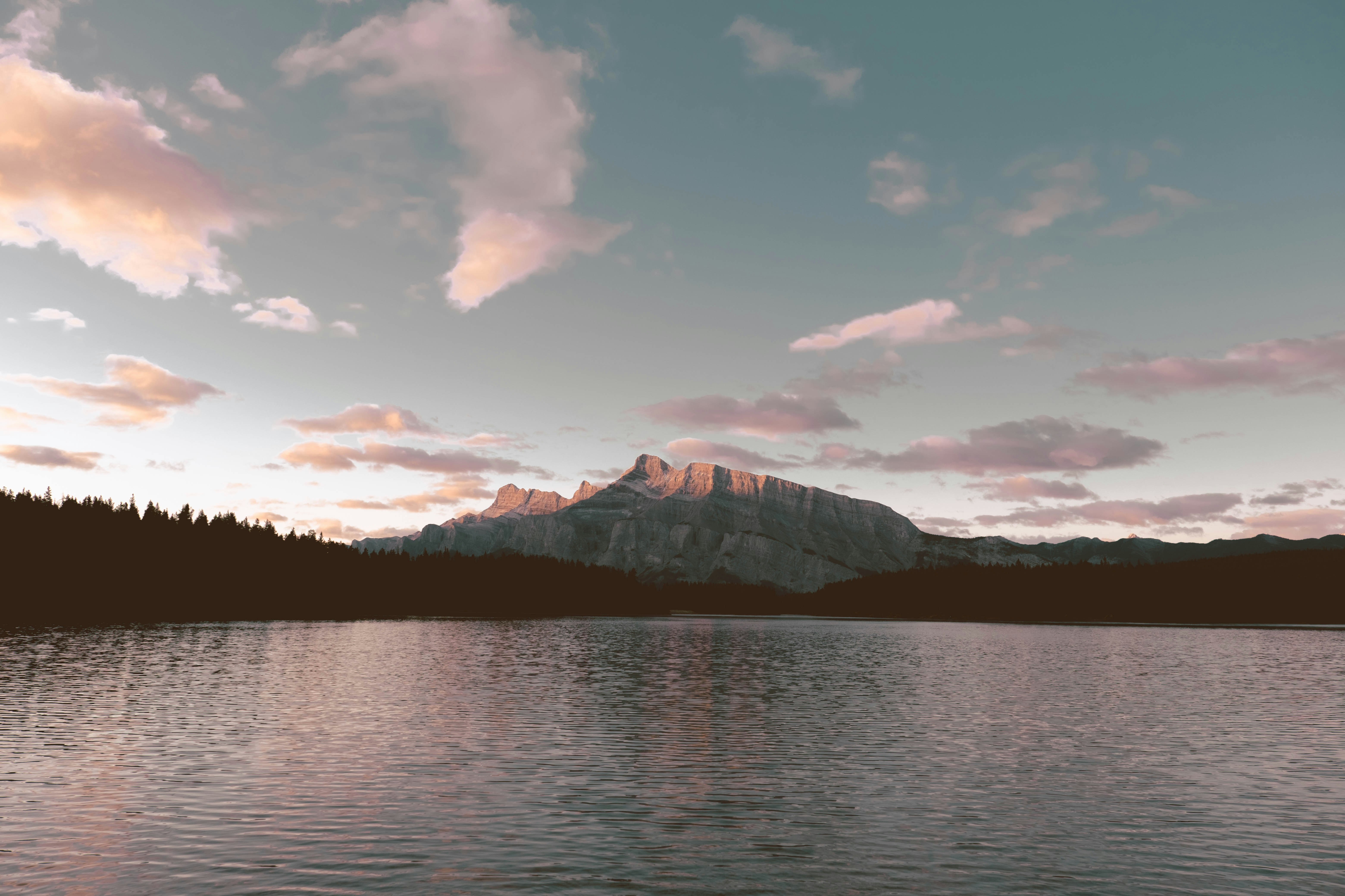 body of water near mountain under cloudy sky during daytime